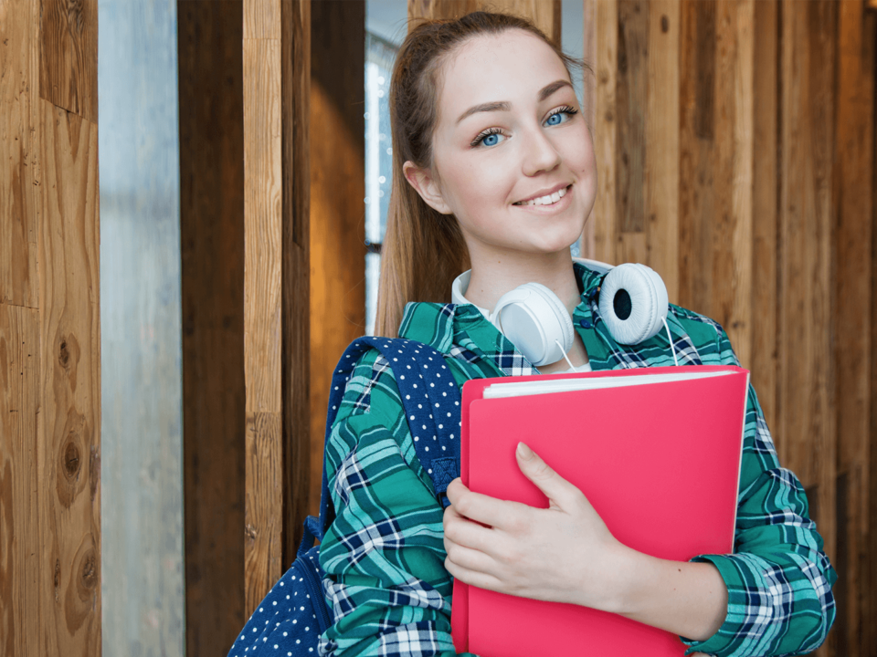 Female high school student wearing headphones and holding books