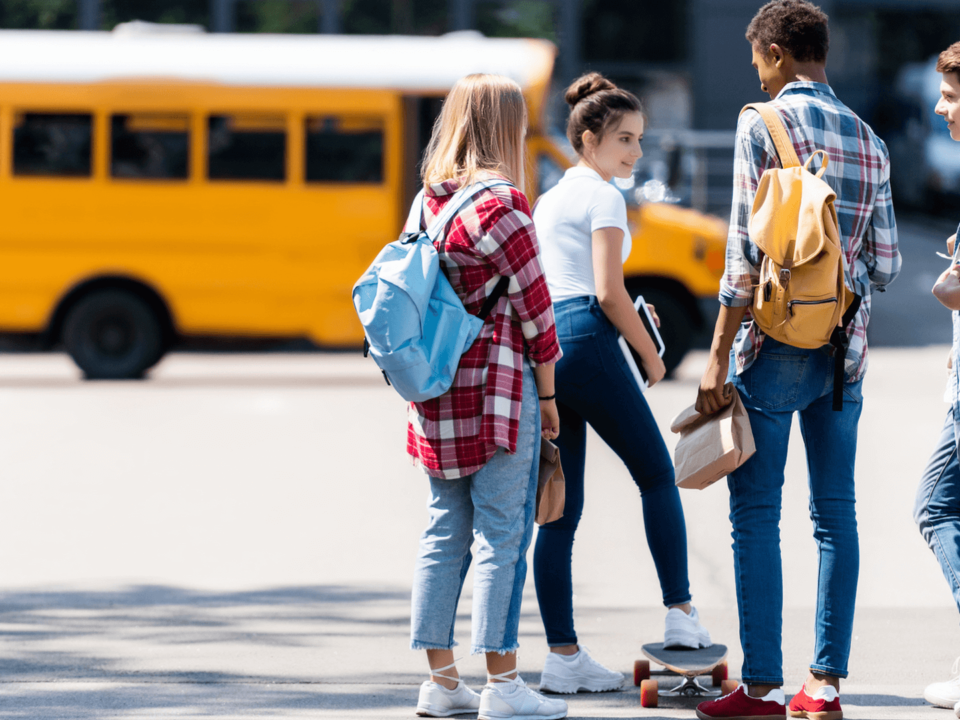 Teens talking outside of school bus